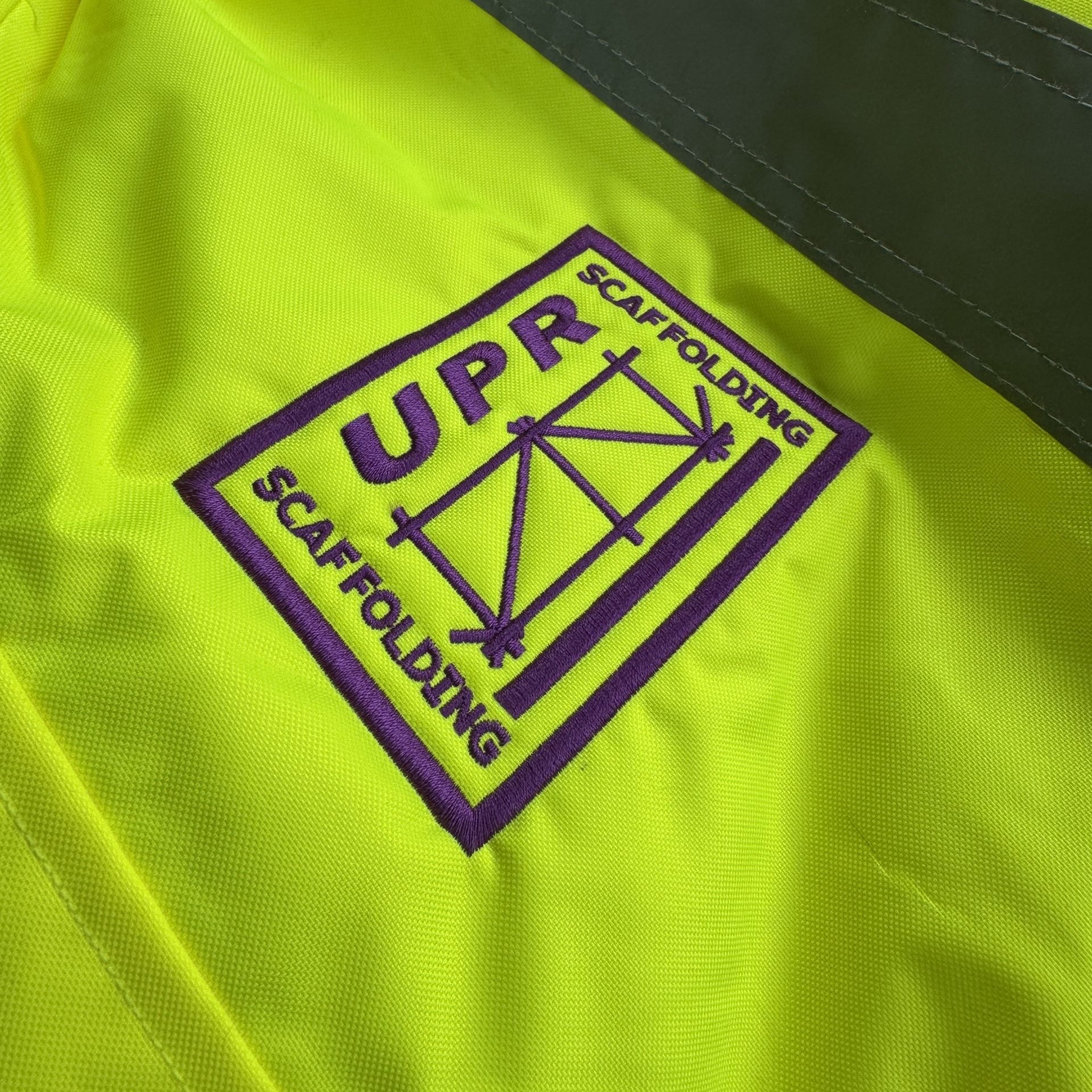 Yellow jacket with UPR Scaffolding logo on a black background